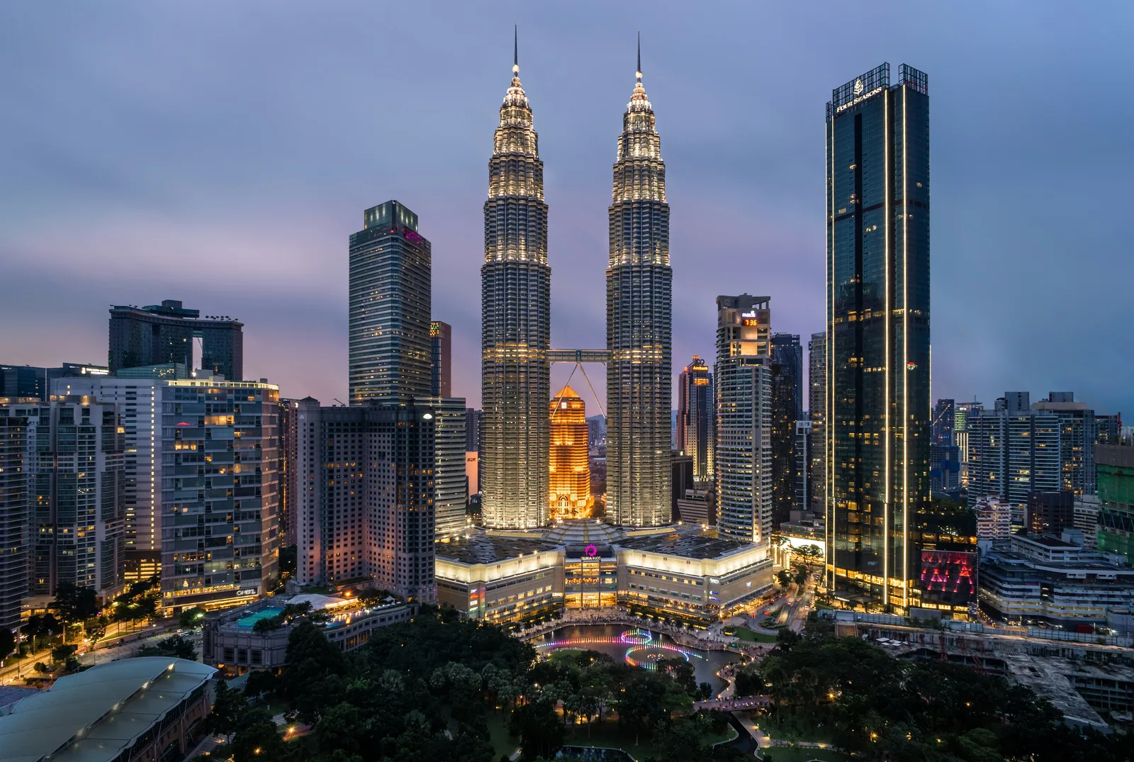 The Petronas Twin Towers illuminated above the Kuala Lumpur skyline at dusk